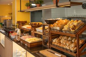 a buffet line with various types of bread and pastries at Uniclass Hotel Lapa in São Paulo