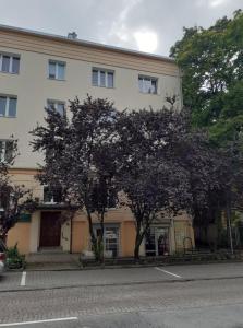 Un gran edificio blanco con árboles delante. en Apartament Mickiewicza, en Olsztyn