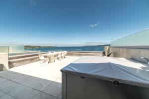 a balcony with a view of the ocean with tables and chairs at Sacred Waters Taupo in Taupo