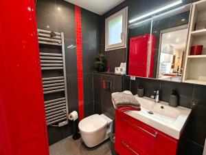 a red bathroom with a white toilet and a sink at Appartement toit terrasse Nice-ouest avec parking, clim et piscine in Nice +12 photos