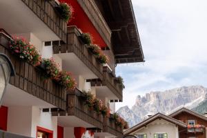 budynek z kwiatami na balkonach z górami w tle w obiekcie Hotel Grohmann w mieście Campitello di Fassa