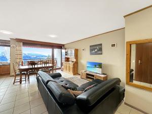 a living room with a black leather couch and a television at Alpine Evasion - Crans Montana - Swiss Alps in Crans-Montana