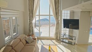 a living room with a couch and a large window at Qoople Villa Tepe with infinity pool and panoramic view in Alanya