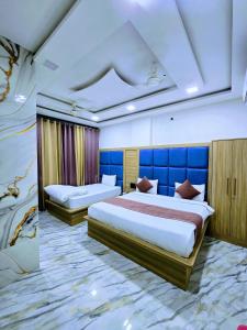 马图拉Premium Hotel Aarav Grand - Mathura Central - 5 Min distance from Railway Station的一间卧室，有两张床和一面蓝色的墙
