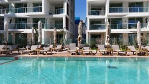 a swimming pool with lounge chairs and a building at Rivi Luxury 42 Suites - By SEAELO EILAT in Eilat