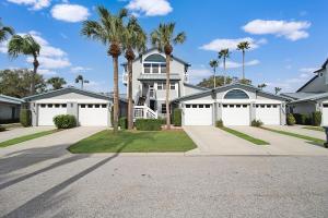 a large house with white garage doors and palm trees at Updated 2BR Siesta Key condo with private beach access in Siesta Key