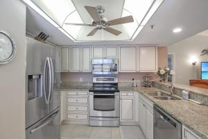 a kitchen with white cabinets and a ceiling fan at Updated 2BR Siesta Key condo with private beach access in Siesta Key