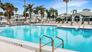 a large blue swimming pool with chairs and palm trees at Updated 2BR Siesta Key condo with private beach access in Siesta Key