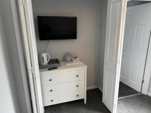 a bedroom with a dresser with a tv on the wall at The Den and Orchard in Frome