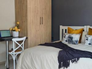 セツンダにあるTshepang Apartments Secundaのベッドルーム1室(ベッド1台、ノートパソコン付きのデスク付)
