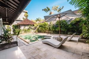 um pátio exterior com um guarda-sol e uma piscina em Sari Temuku Villa em Seminyak