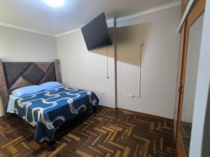 a bedroom with a bed with a tv on the wall at Hospedaje Wily Tacna in Tacna