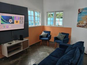 a living room with a couch and a flat screen tv at Paraíso de Verão - Disfrute final de semana em Casa Exclusiva com piscina, sinuca e churrasqueira Aluguel para temporada em Riviera de São Lourenço in Bertioga