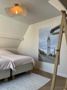 a bedroom with a bed and a picture of a lighthouse at Salty Breeze - Free Parking, quietly situated close to centre and beach! in Noordwijk