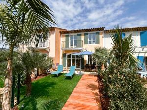 una casa con un cortile con sedie blu e palme di Maison 20 du Lac Les Restanques a Grimaud