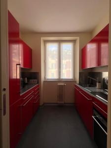 an empty kitchen with red cabinets and a window at La casa di Eli in Genoa