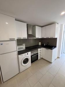 a kitchen with white cabinets and a washing machine at Angel 29 in Vinarós