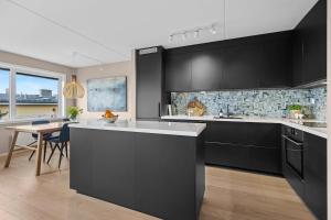 Una cocina grande con gabinetes negros y una mesa. en Modern 3 bedroom apartment - 4 minute walk from metro - top floor baclony view, en Oslo