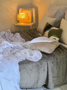 a messy bed with a lamp on a table at Le Rodrigues - plages - parking - clim - wifi in Saint-Gilles les Bains
