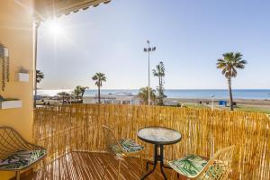 een patio met een tafel en stoelen en het strand bij A&N Los Carmenes, Torre del Mar in Torre del Mar