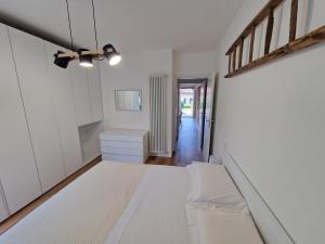 Un dormitorio con una cama blanca y un pasillo. en Cà del Luis, en Lierna