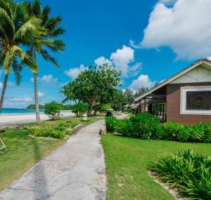 a house on the beach with palm trees and a sidewalk at Mayang Sari Beach Resort in Lagoi