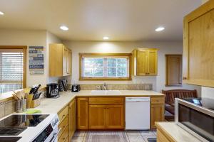 a kitchen with wooden cabinets and a white dishwasher at Seas the Day in Shorepine in Pacific City +36 photos