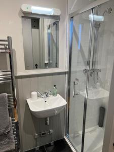 a bathroom with a sink and a shower with a mirror at Balnain Street Cottage in Inverness +7 photos