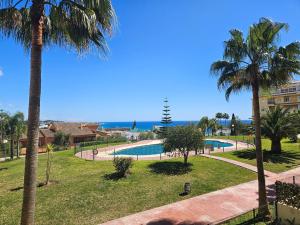 a resort with a swimming pool and palm trees at Two bedroom apartment with pool & sea views in Mijas Costa