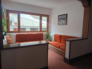 a living room with an orange couch and a window at Fiocco di sole Apartment in Sestriere