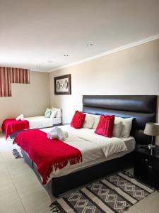 a bedroom with two beds with red pillows at Cavallo Guesthouse in Windhoek
