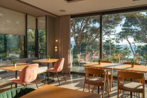 a restaurant with tables and chairs and large windows at Glow Boutique Hotel & Suites in Sarandë
