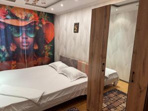 een slaapkamer met een schilderij van een vrouw met een zonnebril bij Ермекова 52 in Karagandy