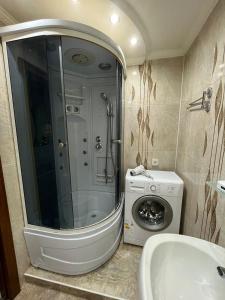een badkamer met douche en wasmachine bij Ермекова 52 in Karagandy