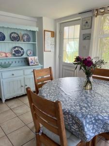 a dining room table with a vase of flowers on it at Ancaire Cottage Kilbronogue. Schull in Schull