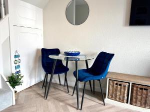 a table with two blue chairs and a mirror at 1 Bed House On The Beach in St Peter