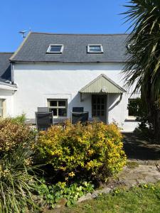 a white house with chairs and flowers in front of it at Ancaire Cottage Kilbronogue. Schull in Schull