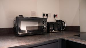 a microwave sitting on top of a kitchen counter at Prestige Stays Cardiff Modern 1-Bed Apartment near City Centre Wi-Fi & Lockbox Check-In in Cardiff +10 photos