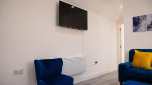 a living room with two blue chairs and a flat screen tv at Prestige Stays Cardiff Modern 1-Bed Apartment near City Centre Wi-Fi & Lockbox Check-In in Cardiff