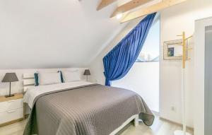 a bedroom with a bed with blue curtains and a window at Stunning Home In Niechorze With Sauna in Niechorze