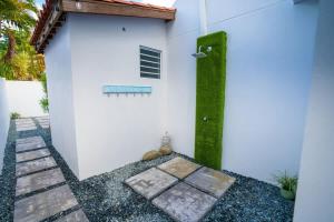 a white house with a green wall and a walkway at Romantic Dorado Beach Studio in Dorado
