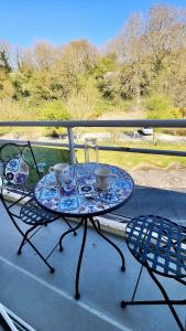 una mesa de cristal con 2 sillas y vasos en el balcón en Laurence's Home, en Veules-les-Roses