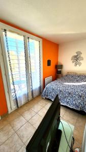 1 dormitorio con paredes de color naranja, 1 cama y TV en Laurence's Home, en Veules-les-Roses 3 fotos más