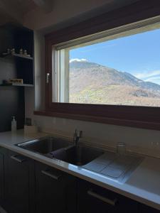 a kitchen sink with a window with a mountain view at Arzo Mountain Chalet in Morbegno +41 photos