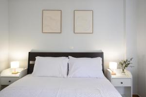 une chambre avec un lit blanc avec deux tableaux au mur dans l'établissement Saronida Seaside Serenity, à Saronida