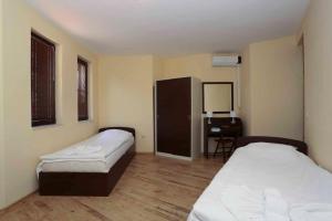 a room with two beds and a desk and a mirror at Sozopol Dreams Apartments in Sozopol