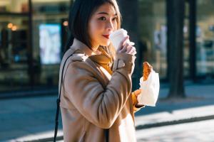 una mujer con una chaqueta de cuero sosteniendo una taza de comida en Garner Hotel Hamburg - Wandsbek Marktplatz by IHG, en Hamburgo