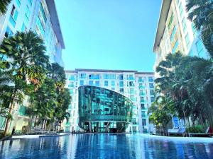 una piscina frente a un edificio con palmeras en City Center Residence NEW, en Pattaya central