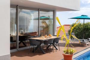 a patio with a table and chairs and a pool at Private pool and sea view - Tropical Villa in Arco da Calheta