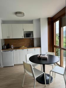 a kitchen with a black table and white chairs at Apartamentos Boutique Don Miguel in Noja